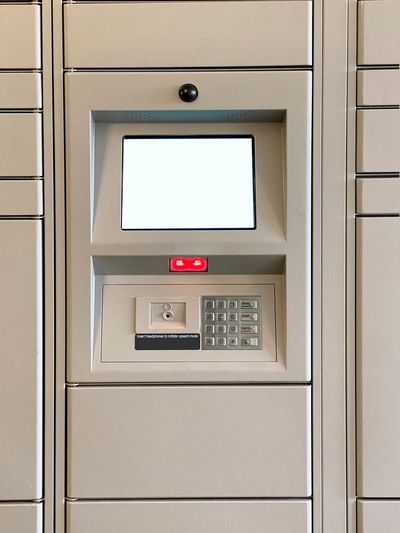Automated locker system with a blank touchscreen, keypad, headphone jack, and red indicator light