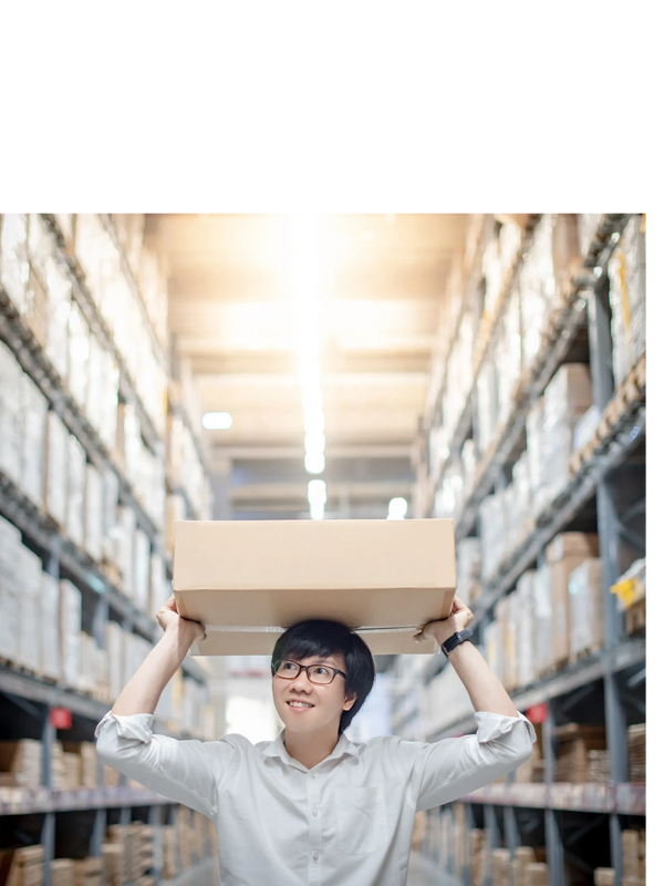 Man carrying a box on his head in a warehouse aisle.