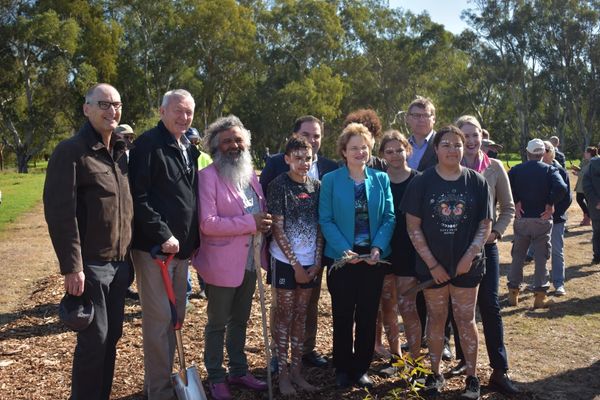 Group of diverse people posing outdoors at a planting event.