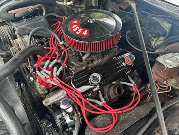 A detailed view of a car engine with red ignition wires and a 455-4 air filter cover.