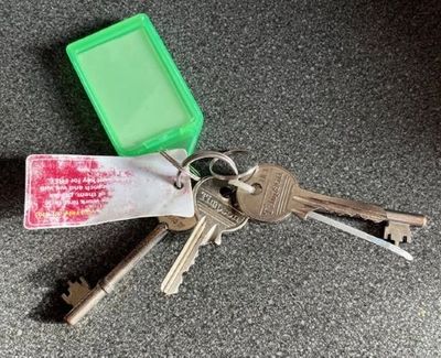 A set of keys with green and white key tags on a dark surface.