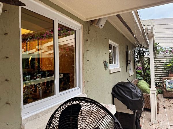 Cozy backyard patio with grill, fan, and outdoor seating under a pergola.