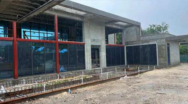 Modern building under construction with large glass panels and red frames.