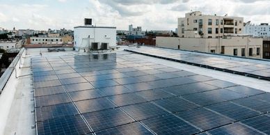 Solar panels installed on a rooftop reflecting the cloudy sky.