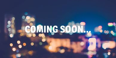 Blurred city lights with the text 'COMING SOON...' in bold white letters.