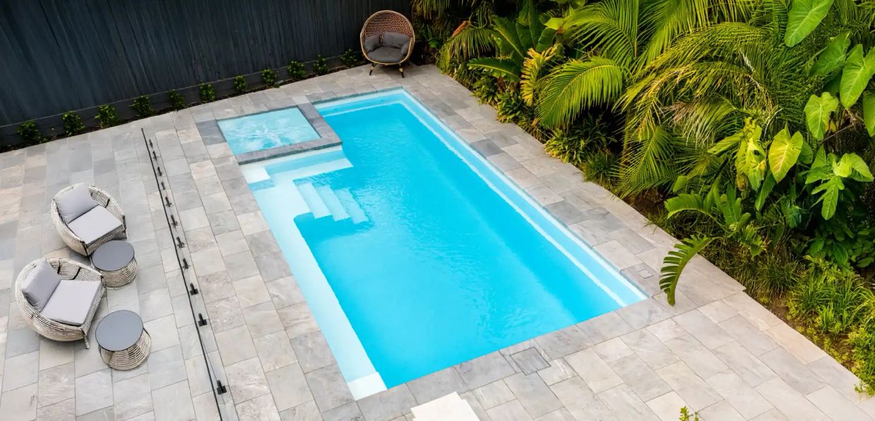 Modern backyard pool with lounge chairs and lush greenery.