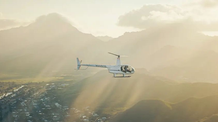 Robinson helicopter flying above Oahu’s green mountain scenery