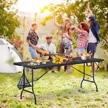 Friends enjoying music and food around a picnic table outdoors.