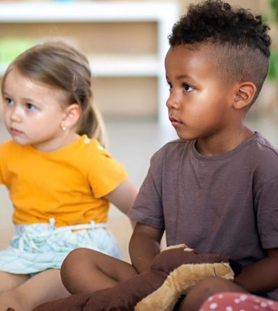Two kids sitting attentively indoors.