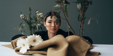 Asian woman behind flowers modernly dressed looking at camera