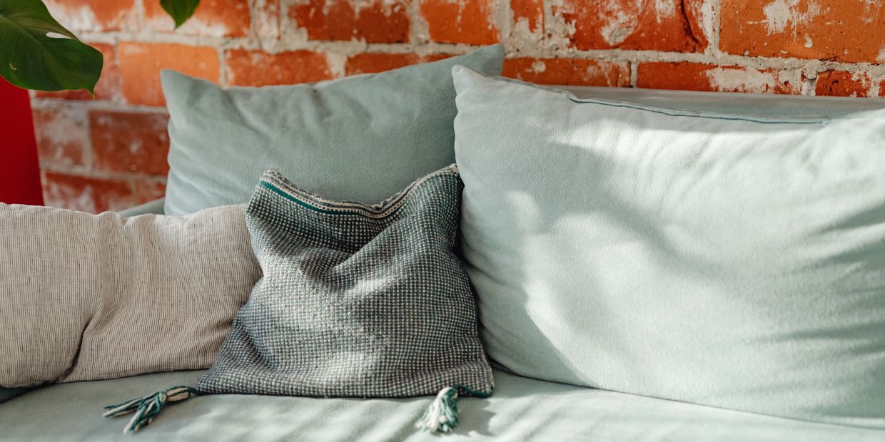 Seafoam green cozy couch in front of brick wall