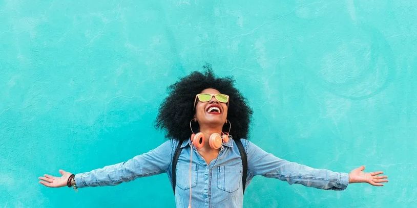 African American woman laughing in front of blue wall