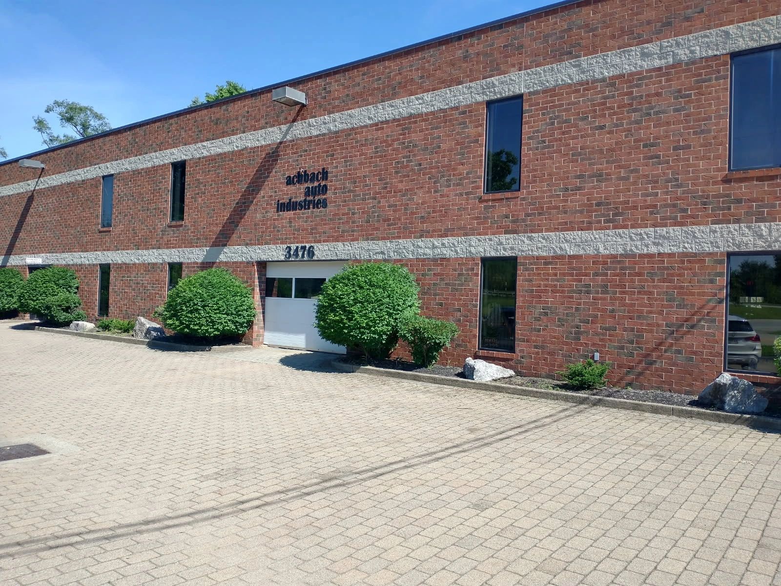 Brick commercial building with bushes and clear sky.