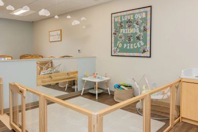 A cozy, safe baby play area with toys and a colorful wall sign.