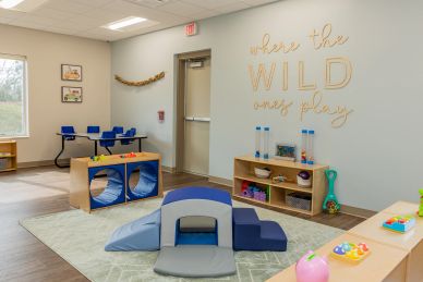 Indoor kids' playroom with soft toys and furniture.