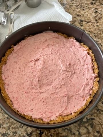 Unbaked cheesecake with pink filling in a springform pan.