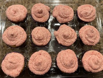 Pink frosted cupcakes in a plastic container.