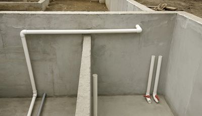 Newly installed white PVC pipes in a concrete structure.