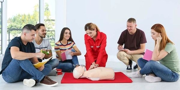 Group learning CPR with instructor demonstrating on a mannequin.