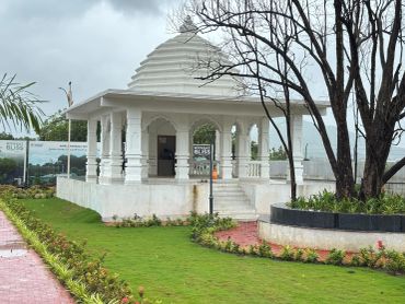 White pavilion with traditional design surrounded by greenery.