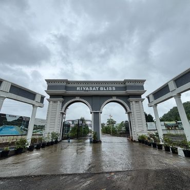 Entrance gate of Riyasat Bliss under a cloudy sky.