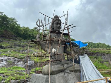 Stone statue under construction surrounded by bamboo scaffolding.