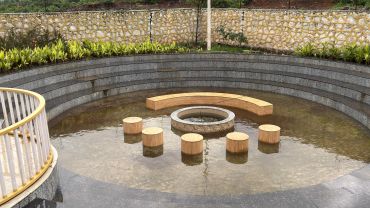 Outdoor seating area with water and wooden stools.