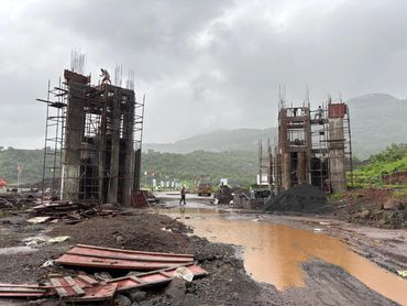 Construction site with workers and scaffolding under cloudy sky.