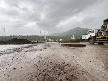 Construction site with truck and muddy ground under cloudy sky.