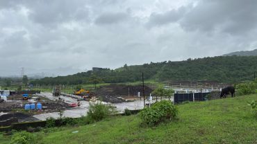 Green landscape with cloudy sky and construction site.