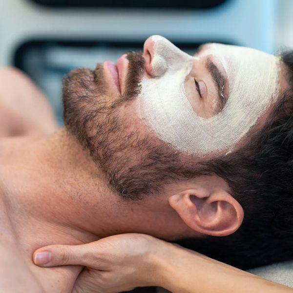Man with a facial mask relaxing during a massage.