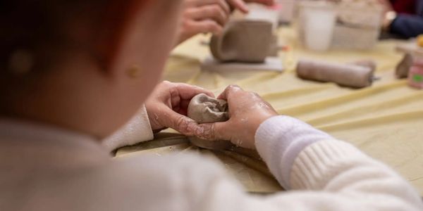 Person shaping clay with hands in a pottery workshop.