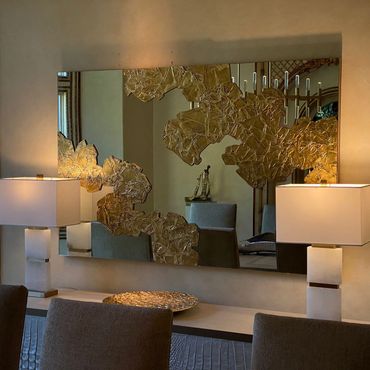 Elegant dining area with decorative gold-accented mirror and modern lamps.