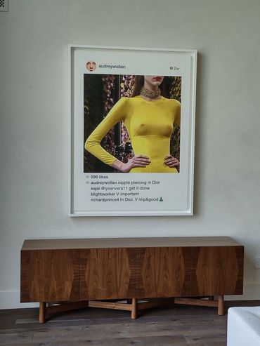Modern framed Instagram art above a wooden cabinet in a minimalist room.