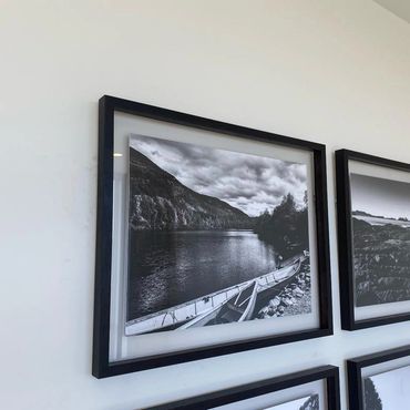 Black and white framed photos of landscapes on a white wall.