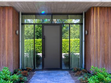 Geïsoleerde aluminium buitendeur met vleugeloverdekkend paneel. Strakke lijnen en grote zijlichten.