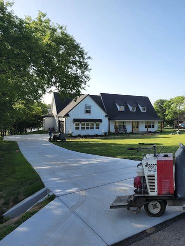 Concrete being poured into a wheelbarrow at a residential driveway.