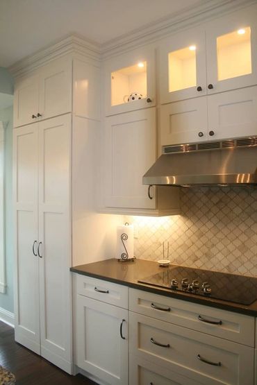 A kitchen with an exhaust fan and white cabinetry