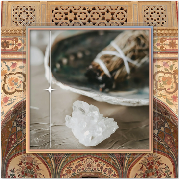 A sage smudge stick burns in a shell by a quartz crystal cluster