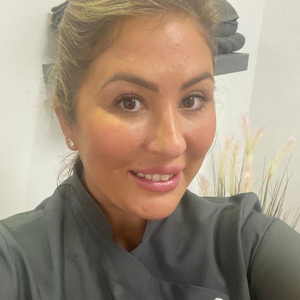 Smiling woman in a gray top with natural makeup.