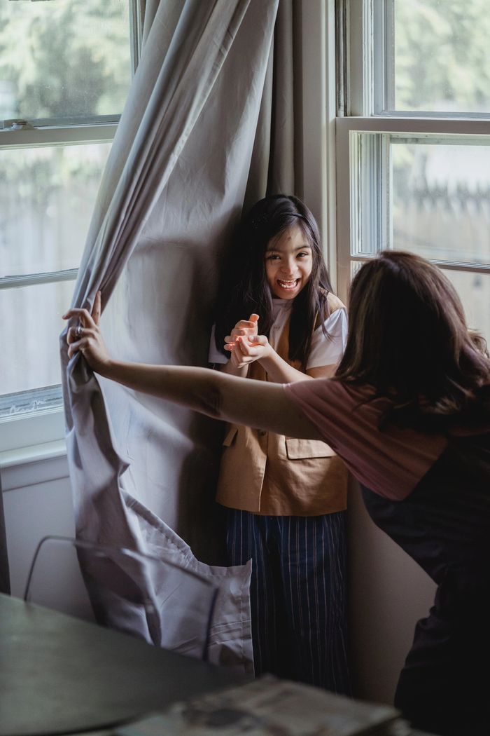 Little girl playing hide and seek with her teacher.