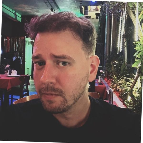Man with short hair and beard in a dimly lit restaurant.