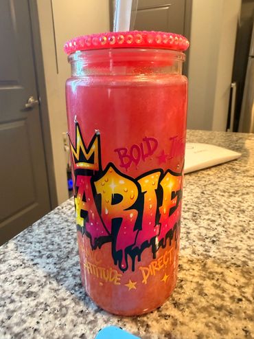 A vibrant pink drink in a graffiti-style jar with a decorated lid.