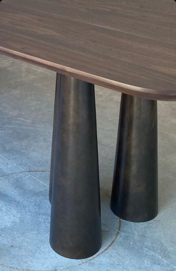 Close-up of a wooden table with unique dark, tapered cylindrical legs.
