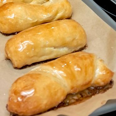 Golden brown glazed pastries cooling on parchment paper.