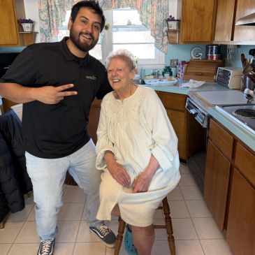 Young man and elderly woman smiling in a kitchen.