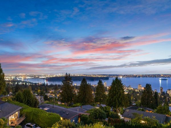 City skyline at dusk with water and colorful clouds.