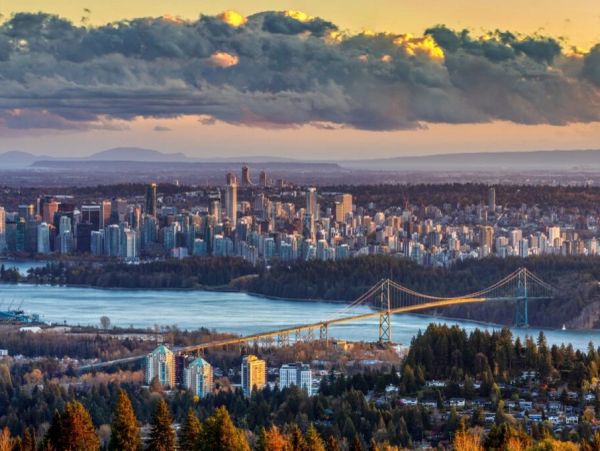 Sunset view of city skyline with a bridge and river.
