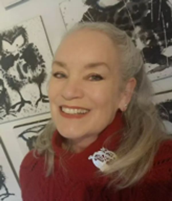 Smiling woman in red sweater with artistic black and white paintings behind her.