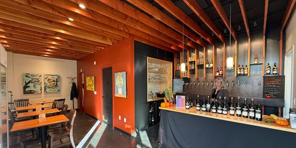 Cozy wine bar with wooden ceiling and warm lighting.